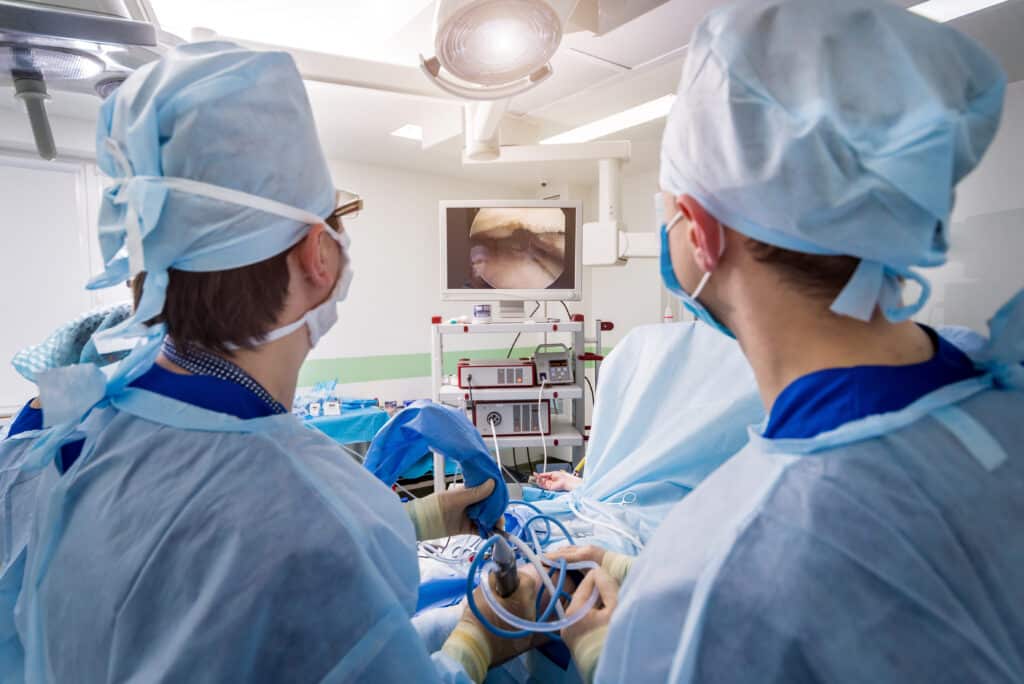 Orthopedic surgeons in the operating room with modern arthroscopic tools performing arthroscope surgery