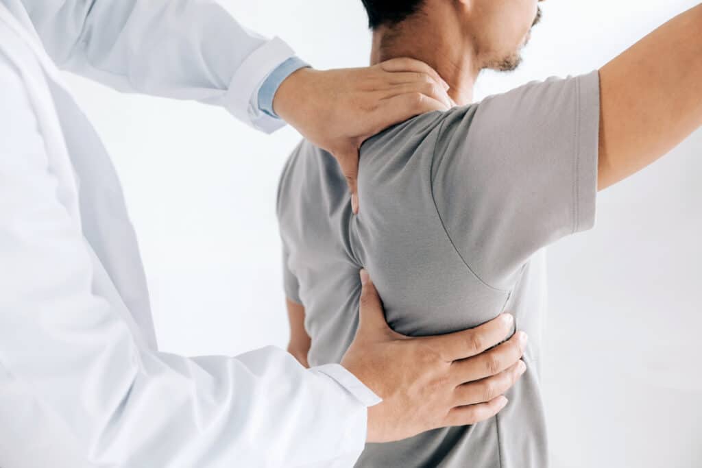 Patient receiving healing back and shoulder pain treatment from physician
