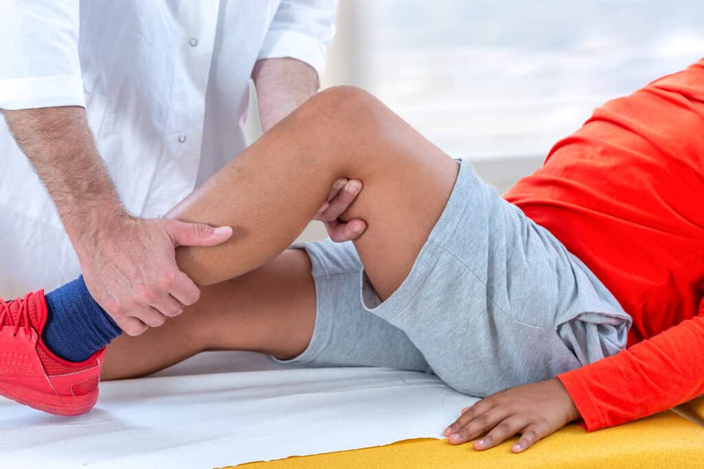 Doctor examining boys leg because of injury