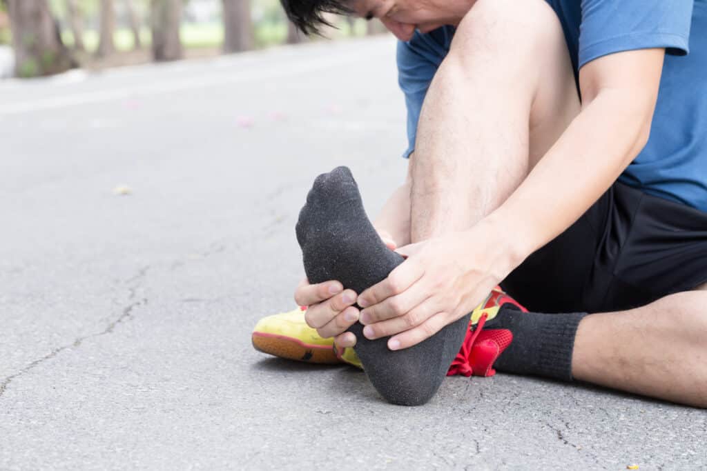 male holding foot in pain on the concrete