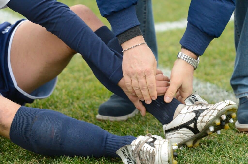child with soccer injury sitting on field holding ankle