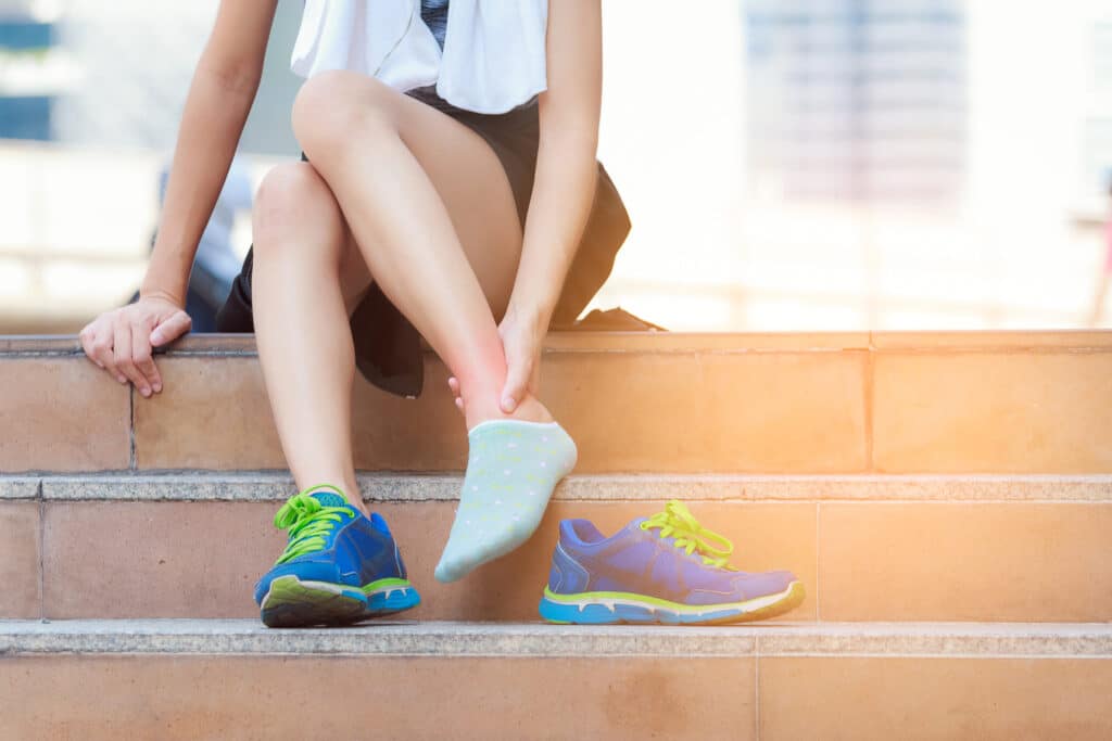 female runner sitting on steps with ankle sprain